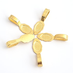 May include: Five gold-toned metal pendant bails with a decorative oval design. The bails are arranged in a star shape.