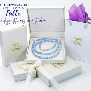 a collection of jewelry items, including a necklace, a box, and a gift bag, all presented in a white and gold color scheme.