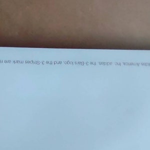 May include: A corner of a white paper with text in a light gray font. The text reads "&copy; 2000 adidas America, Inc. adidas, the 3-Bars logo, and the 3-Stripes mark are registered trademarks of the adidas Group."