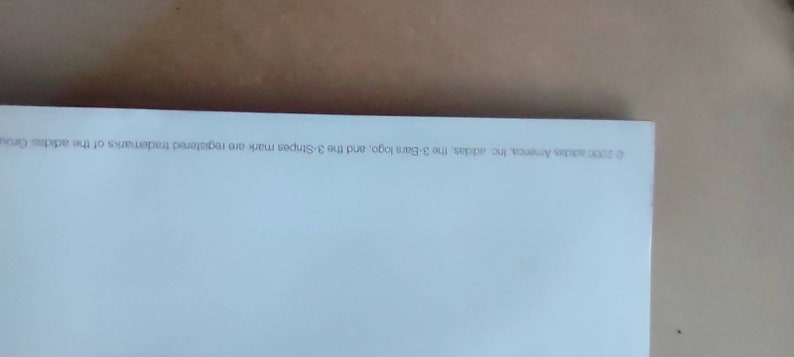 May include: A corner of a white paper with text in a light gray font. The text reads "&copy; 2000 adidas America, Inc. adidas, the 3-Bars logo, and the 3-Stripes mark are registered trademarks of the adidas Group."
