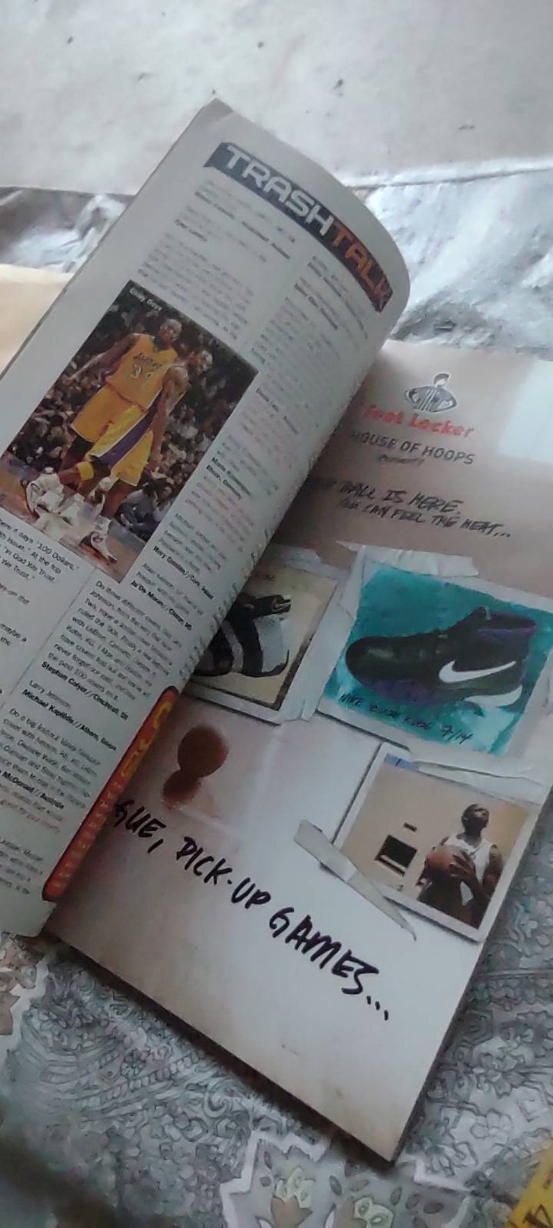 May include: An open magazine with the title "TRASH TALK" visible. The pages feature basketball-related content, including images of players in action and advertisements for athletic footwear. The phrase "SUE, PICK-UP GAMES..." is written on the page.