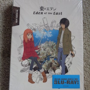 May include: A sealed Blu-ray box set of "Eden of the East" anime series. The cover features two anime characters and a background of sketched technology. The title is in English and Japanese. A blue sticker indicates Blu-ray availability.