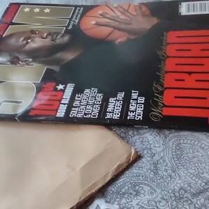May include: A magazine cover featuring Michael Jordan with a basketball. The magazine is titled "SLAM" with the word "JORDAN" prominently displayed. Additional text includes "World Exclusive" and "What the Game's Been Missing".
