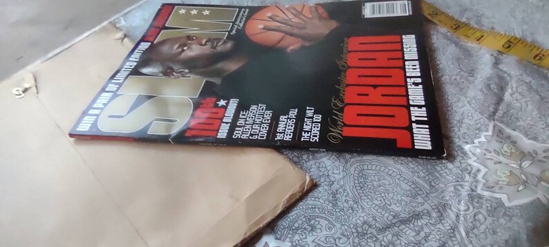 May include: A magazine cover featuring Michael Jordan with a basketball. The magazine is titled "SLAM" with the word "JORDAN" prominently displayed. Additional text includes "World Exclusive" and "What the Game's Been Missing".