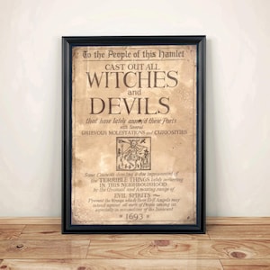 May include: A framed wall art print featuring aged, parchment-style paper with dark brown text that reads: To the People of this hamlet CAST OUT ALL WITCHES and DEVILS, including a central woodcut illustration of a figure and the date 1693.