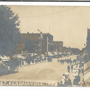 May include: A black and white vintage postcard showing a street scene in Kendallville, Indiana. The postcard reads "Main St. Kendallville, Ind."