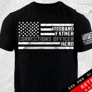 May include: Black and white graphic design of an American flag with the words "Husband, Father, Corrections Officer, Hero" on it. The design is on a black t-shirt.
