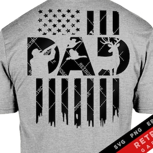 May include: A grey t-shirt featuring a black design of a deer, a hunter, and a bird. The design is set against a black and white American flag. The text "DAD" is incorporated into the design. The bottom of the shirt has the text "SVG PNG EPS AI RETROS GARAGE".