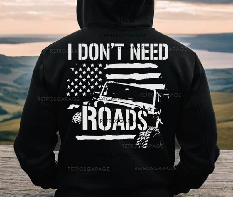 May include: Black hooded sweatshirt with a white graphic of a Jeep driving over an American flag with the text "I don't need roads".