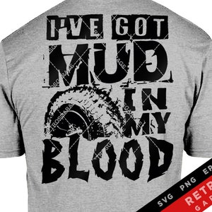 May include: A gray t-shirt with black text that reads "I've got mud in my blood". The text is stylized with a tire tread design. The shirt also has a small American flag on the left sleeve.