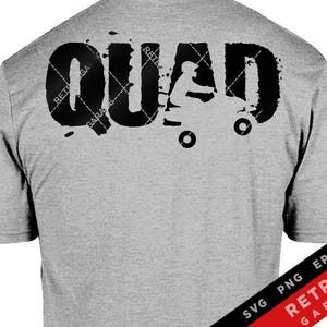 May include: Gray t-shirt with a black graphic of a person riding a quad with the word "QUAD" in large black letters.