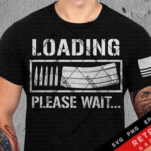 May include: A black t-shirt with a white graphic that says "LOADING... PLEASE WAIT." The graphic features a stylized image of a magazine and bullets. The t-shirt also has a small American flag on the right sleeve.