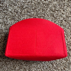May include: Red felt bag insert with a curved top and a single seam down the center.