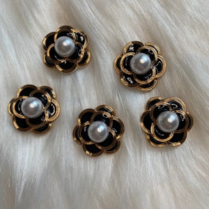 May include: Five black and gold flower-shaped buttons with a white pearl center.