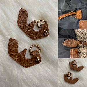 May include: Two brown leather purse straps with gold metal rings and a small gold stud. The straps are shaped like a curved letter E.