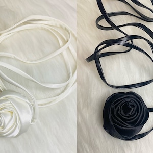 May include: Two satin ribbon sashes with a large rosette at the end. One sash is white and the other is black.