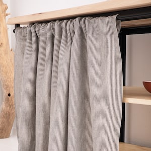 OEKO-TEX certified natural striped linen curtain in a stonewashed grey, draped elegantly as eco-friendly decor for a kitchen cupboard or bathroom shelf.