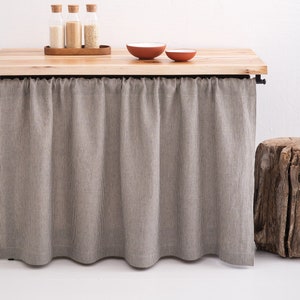 Custom-sized OEKO-TEX certified natural linen curtain in a stonewashed grey, draped elegantly as eco-friendly decor for a kitchen cupboard or bathroom shelf.