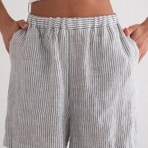 Puede incluir: Shorts a rayas grises y blancas con cintura el&aacute;stica. Los shorts tienen un corte holgado y bolsillos. La tela parece ser lino o un material ligero similar. Los shorts se combinan con un top corto blanco.
