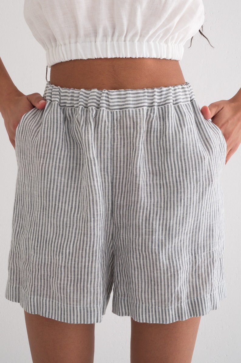 Puede incluir: Shorts a rayas grises y blancas con cintura el&aacute;stica. Los shorts tienen un corte holgado y bolsillos. La tela parece ser lino o un material ligero similar. Los shorts se combinan con un top corto blanco.
