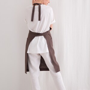 "Back view of a woman wearing a cross-back plus size linen apron in brown, emphasizing comfort for pottery art and crafting."