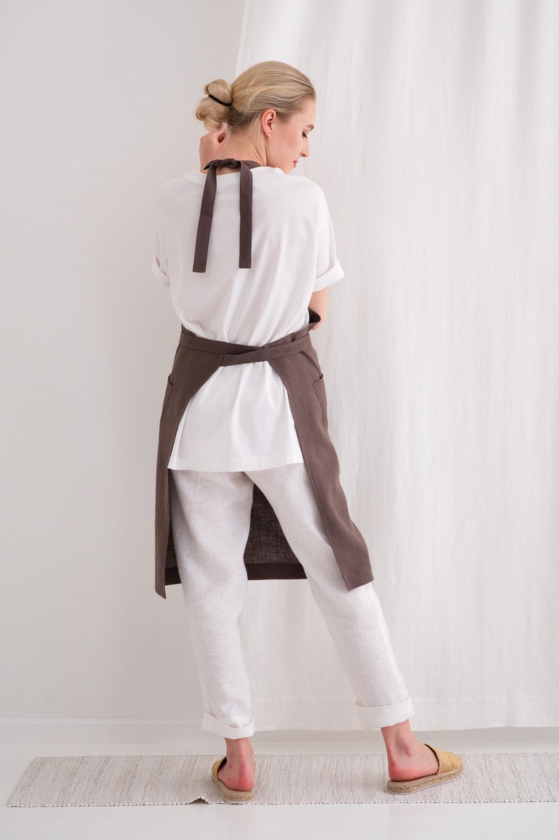 "Back view of a woman wearing a cross-back plus size linen apron in brown, emphasizing comfort for pottery art and crafting."