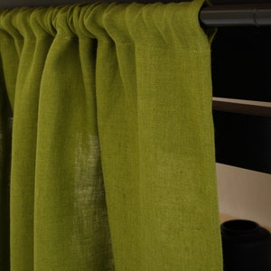 Close-up of moss green stone washed linen privacy curtain with gathered top, against a wooden shelf.