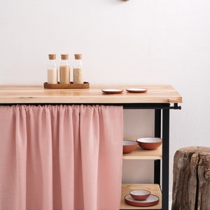 A Natural Linen Curtain in a soft pink hue hangs beneath a kitchen cupboard, showcasing OEKO-TEX certified eco-friendly decor and available in custom sizes.