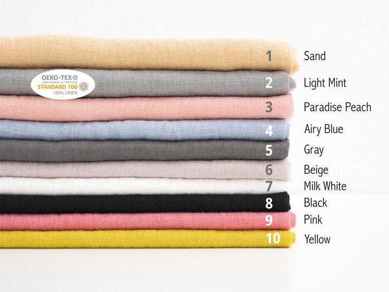 Puede incluir: Una pila de diez muestras de tela de lino en varios colores, incluyendo arena, menta clara, melocot&oacute;n para&iacute;so, azul claro, gris, beige, blanco leche, negro, rosa y amarillo. Las muestras est&aacute;n etiquetadas con n&uacute;meros y nombres de colores. Se ve una etiqueta OEKO-TEX Standard 100.