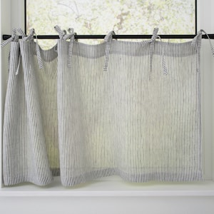 Striped linen cafe curtains with tie tops on a black rod, offering light filtration for a cozy country-style kitchen.