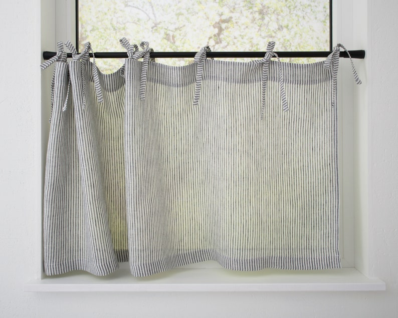 Striped linen cafe curtains with tie tops on a black rod, offering light filtration for a cozy country-style kitchen.