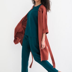 A smiling woman strides forward in a "Comfortable and Stylish Plus Size Linen Maxi Coat with Pockets," a versatile, washed linen duster ideal for any occasion.