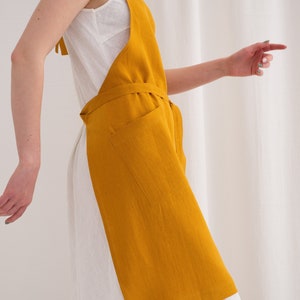 "A woman in a vibrant yellow plus size linen apron suited for painting, showcasing its full coverage and functionality."