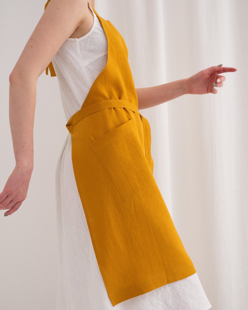 "A woman in a vibrant yellow plus size linen apron suited for painting, showcasing its full coverage and functionality."