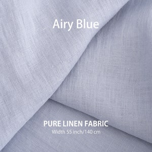 Gentle folds of airy blue pure linen fabric, with a label "Airy Blue" and "PURE LINEN FABRIC, Width 55 inch/140 cm" indicating its quality and dimensions.