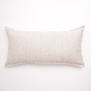 Puede incluir: Una almohada larga y rectangular con un patr&oacute;n de rayas marrones y blancas. La almohada est&aacute; hecha de una tela suave de lino.
