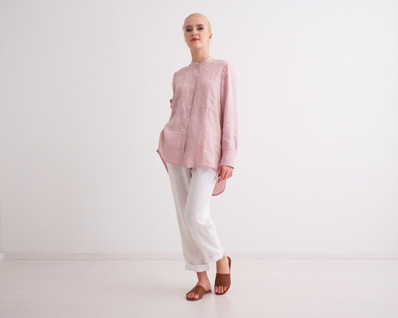 May include: A woman wearing a pink linen shirt with white linen trousers and brown sandals.