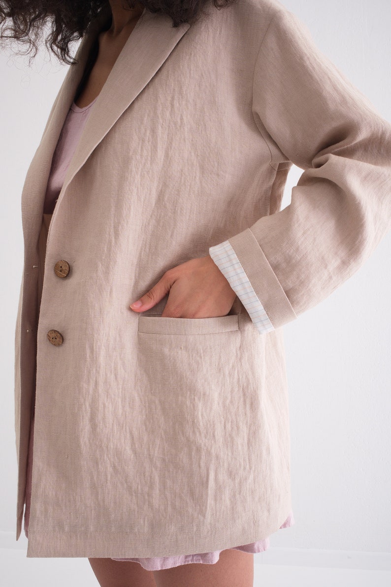 A close-up of a woman's hand in the pocket of a casual loose natural blazer, emphasizing the summer linen jacket's relaxed style and functionality.