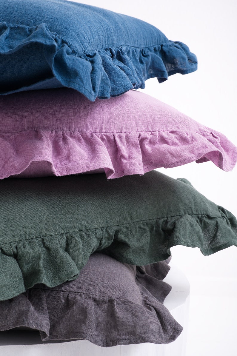 Close-up of stacked ruffled linen pillow shams in blue, pink, green, and gray, for a cozy and stylish bedroom decor.