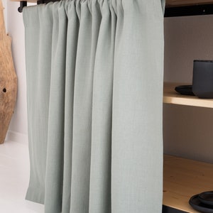 A custom-sized, stonewashed natural linen curtain in sage green, perfect for kitchen cupboards or bathroom shelves, featuring OEKO-TEX certification for eco-friendly decor.