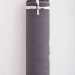 May include: A roll of dark grey linen fabric tied with white ribbon. The fabric is tightly rolled and ready to be used for sewing or crafting projects.