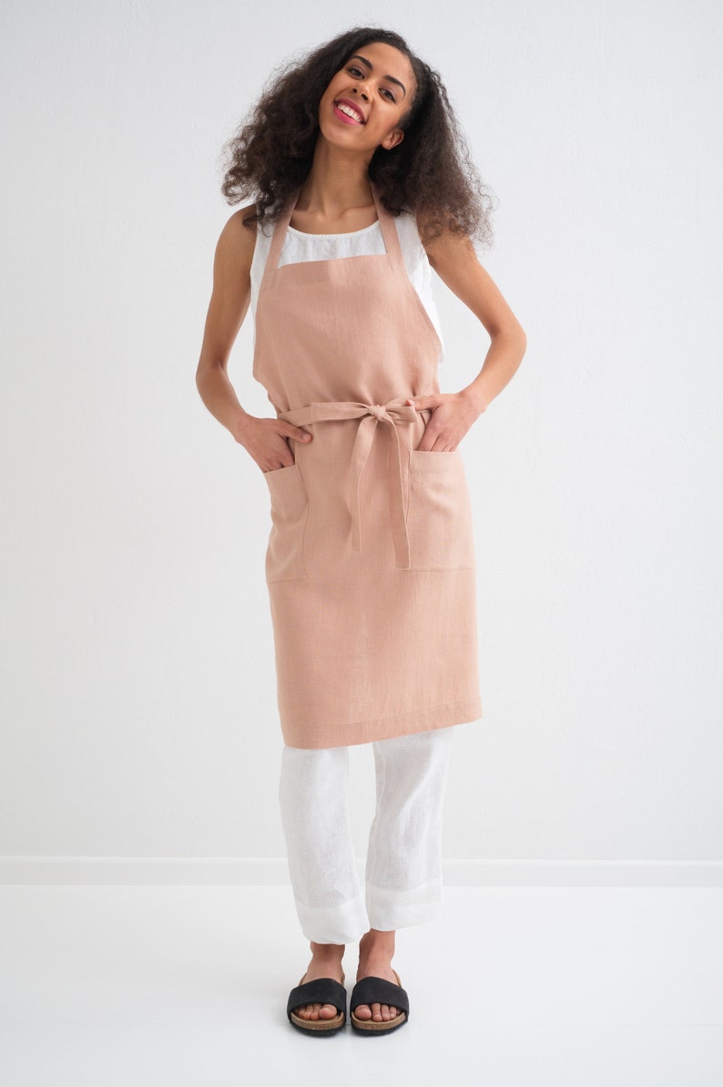 "Confident woman wearing a soft, peach plus size linen apron, ideal for cooking crafts and barbers."
