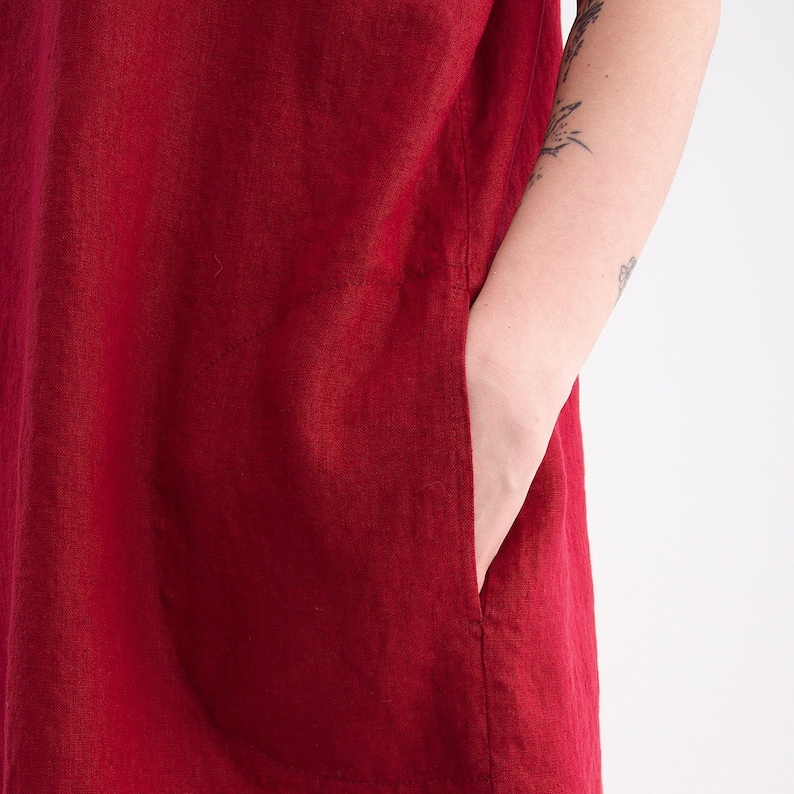 Puede incluir: Un vestido de lino rojo con un solo bolsillo de parche en el lado izquierdo.