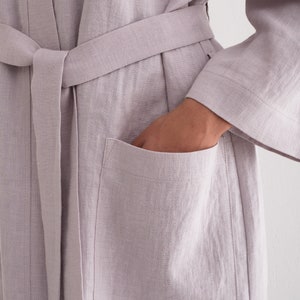 May include: A light purple linen robe with a self-tie belt and a patch pocket on the left side.