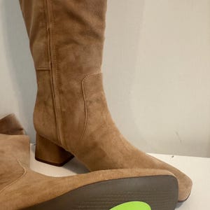 K&ouml;nnte beinhalten: Hellbraune Kniehochstiefel aus Wildleder mit Blockabsatz. Die Stiefel haben eine runde Spitze und einen seitlichen Rei&szlig;verschluss. Die Sohle des Stiefels hat einen gr&uuml;nen Aufkleber mit der Aufschrift "Sam Edelman Wide Calf Tige Large."