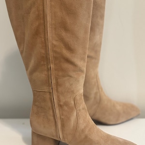 K&ouml;nnte beinhalten: Ein Paar kniehohe Stiefel aus hellbraunem Wildleder. Die Stiefel haben eine quadratische Spitze, einen Blockabsatz und einen Rei&szlig;verschluss an der Seite. Die Stiefel sind etwa 40 cm hoch.