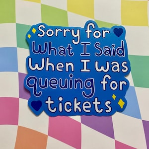 May include: A blue sticker with the text "Sorry for What I Said When I was queuing for tickets" in white. The sticker has a heart and diamond design. The background is a colorful checkered pattern.