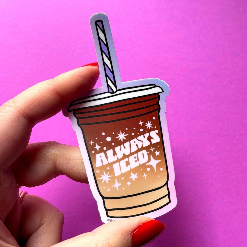 The iced coffee sticker is die cut to the illustration with a purple to pink gradient. The sticker is held for scale over a neon magenta backdrop.