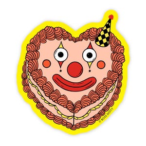 May include: A heart-shaped sticker featuring a clown face design. The clown has large eyes, a red nose, and a wide red smile. The sticker has a yellow border and a party hat. The design is reminiscent of a cake.