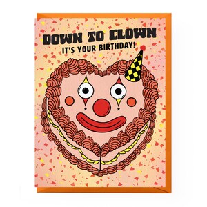 May include: A birthday card with a heart-shaped cake decorated with a clown face. The card has a red, orange, and yellow confetti background and the text "Down to Clown It's your birthday!"